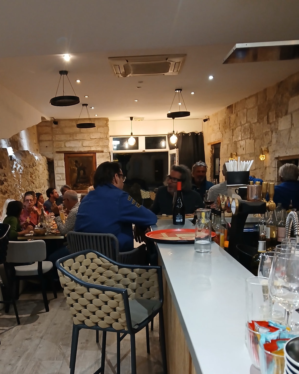 Le comptoir et la salle un soir de service, des clients attablés sous les suspensions
